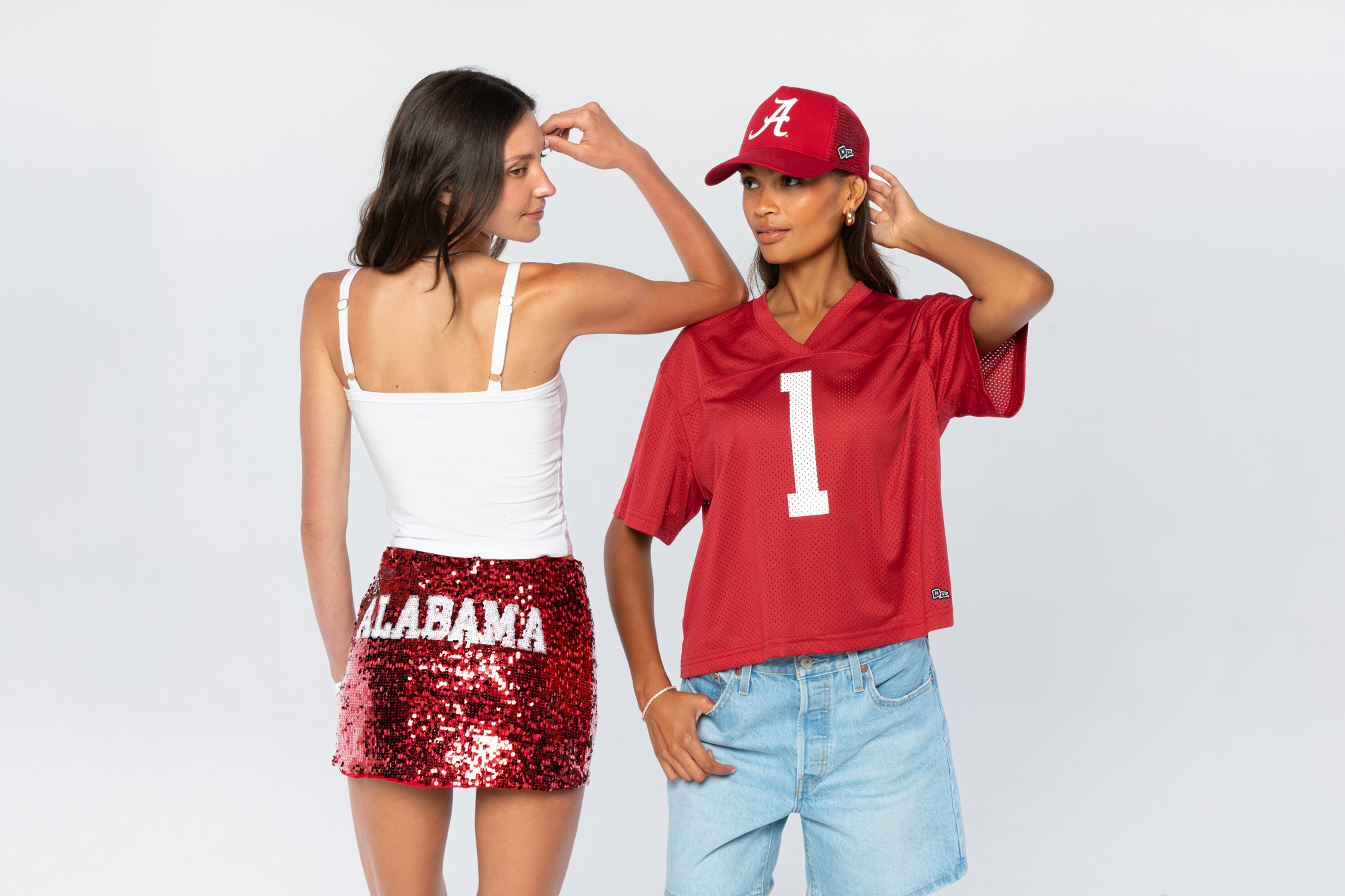 Two women wearing Alabama-themed clothing on a plain background
